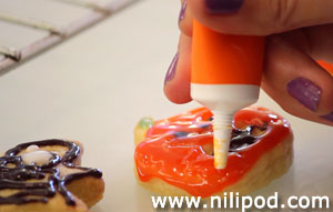 Image of the pumpkin cookie being iced with orange icing