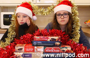 Imge of girls sitting with tinsel, Santa hats and mince pies