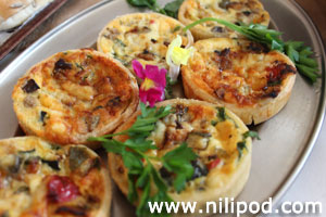 Photo of mini quiches topped with edible flowers