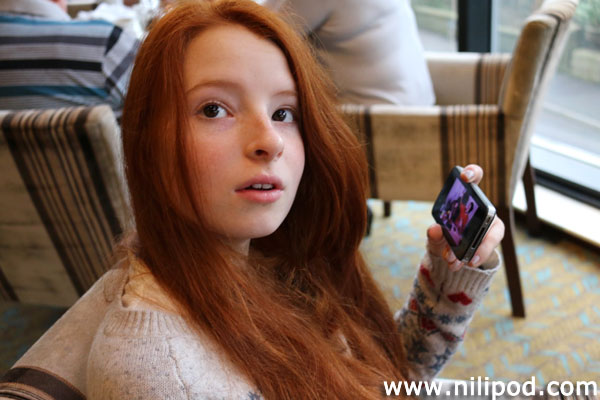 Image of girl sitting in chair, looking at iPhone